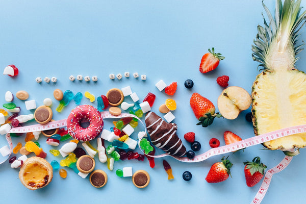 Fruits and sugar candies and a waist measuring tape